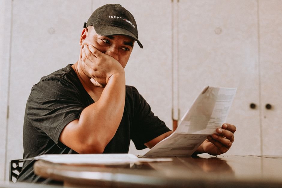 Empresário de restaurante analisando boletos e extrato de FGTS atrasado em um notebook no balcão da cozinha