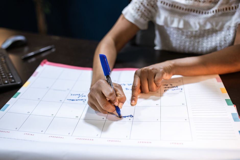 Pessoa marcando datas em um calendário de mesa, planejando a escala da equipe
