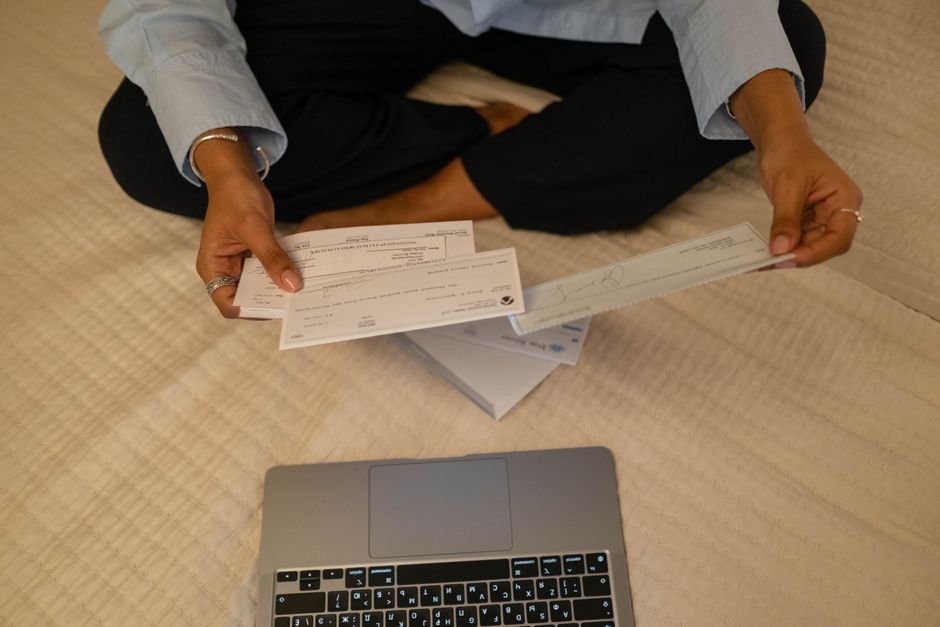 Dona de lavanderia emitindo nota fiscal de serviço em computador no balcão do negócio