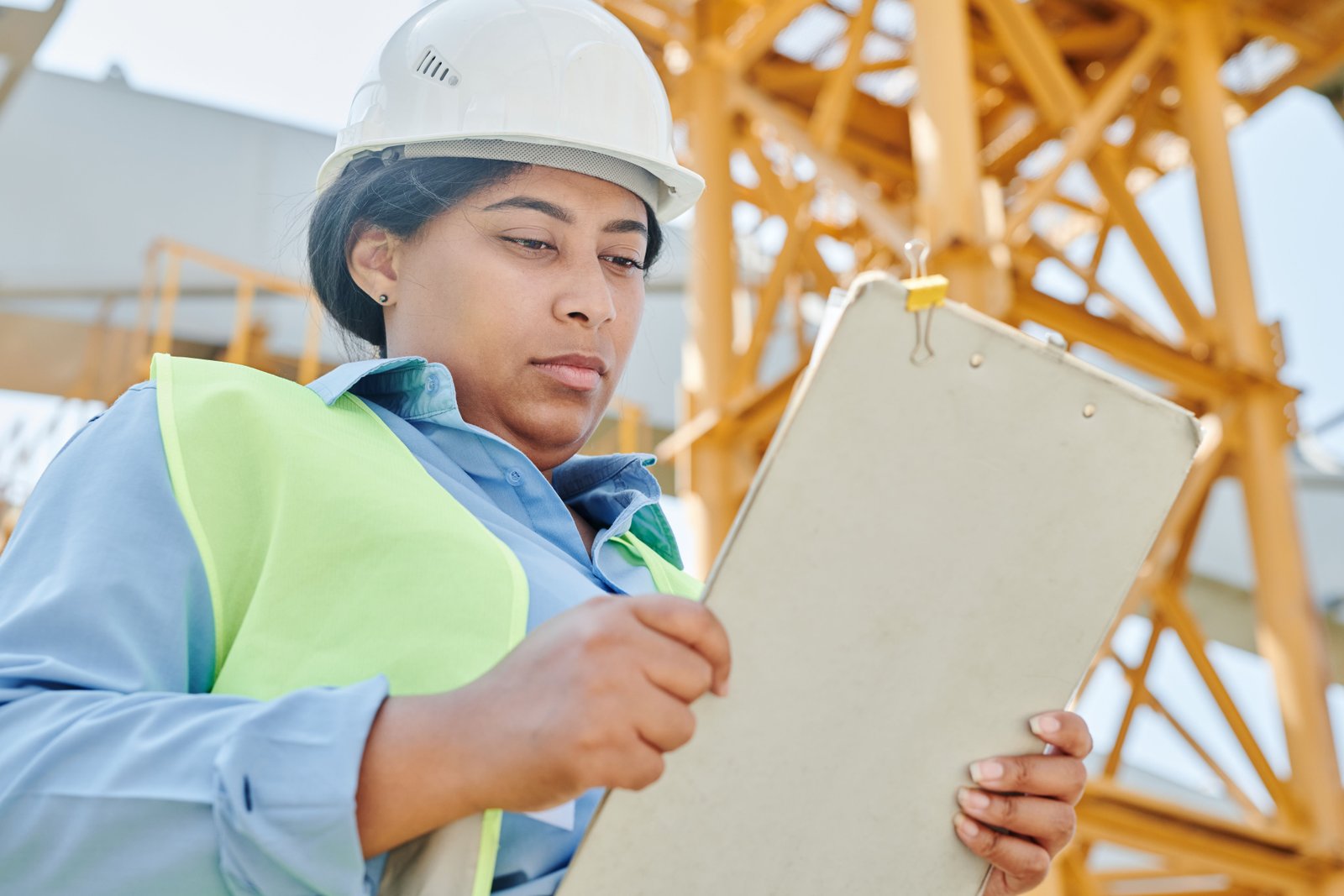 Trabalhador com cinto de segurança e capacete realizando treinamento presencial de acesso por escada fixa em estrutura industrial