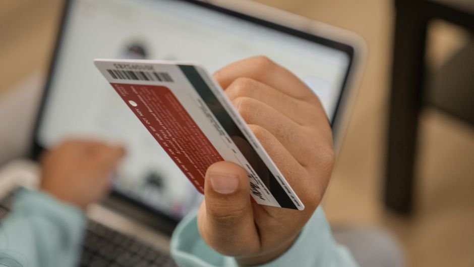 Empresário conferindo no computador o cadastro da empresa no sistema do PAT, com cartões de vale-refeição sobre a mesa