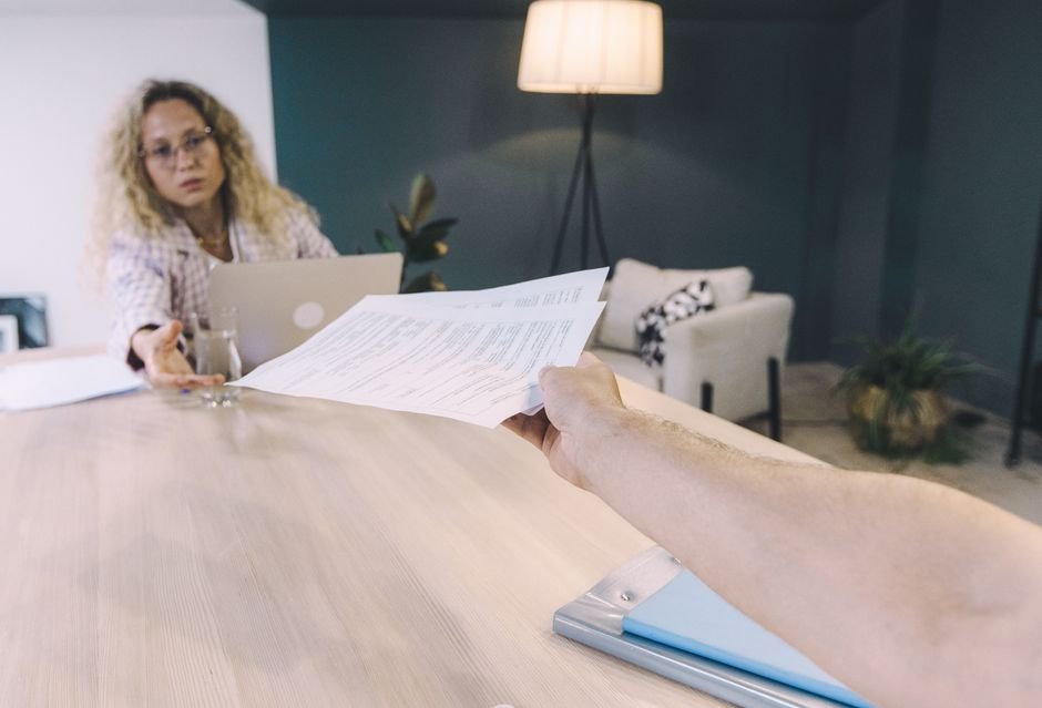 Empresário entregando documento de rescisão para funcionário assinar em ambiente de escritório